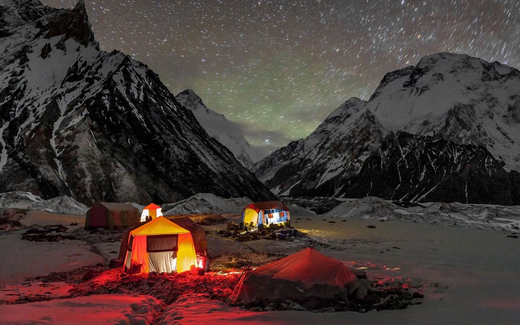 A group of tents lit up under a starry sky.