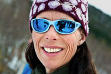 A woman wearing sunglasses and a beanie in the snow.
