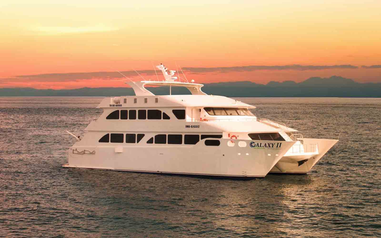 A white boat in the ocean at sunset.