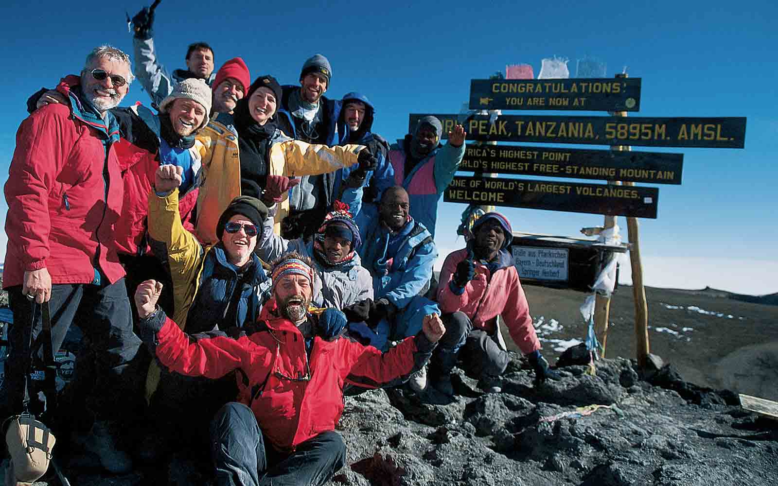 A group of people posing for a picture on top of a mountain during a trekking trip