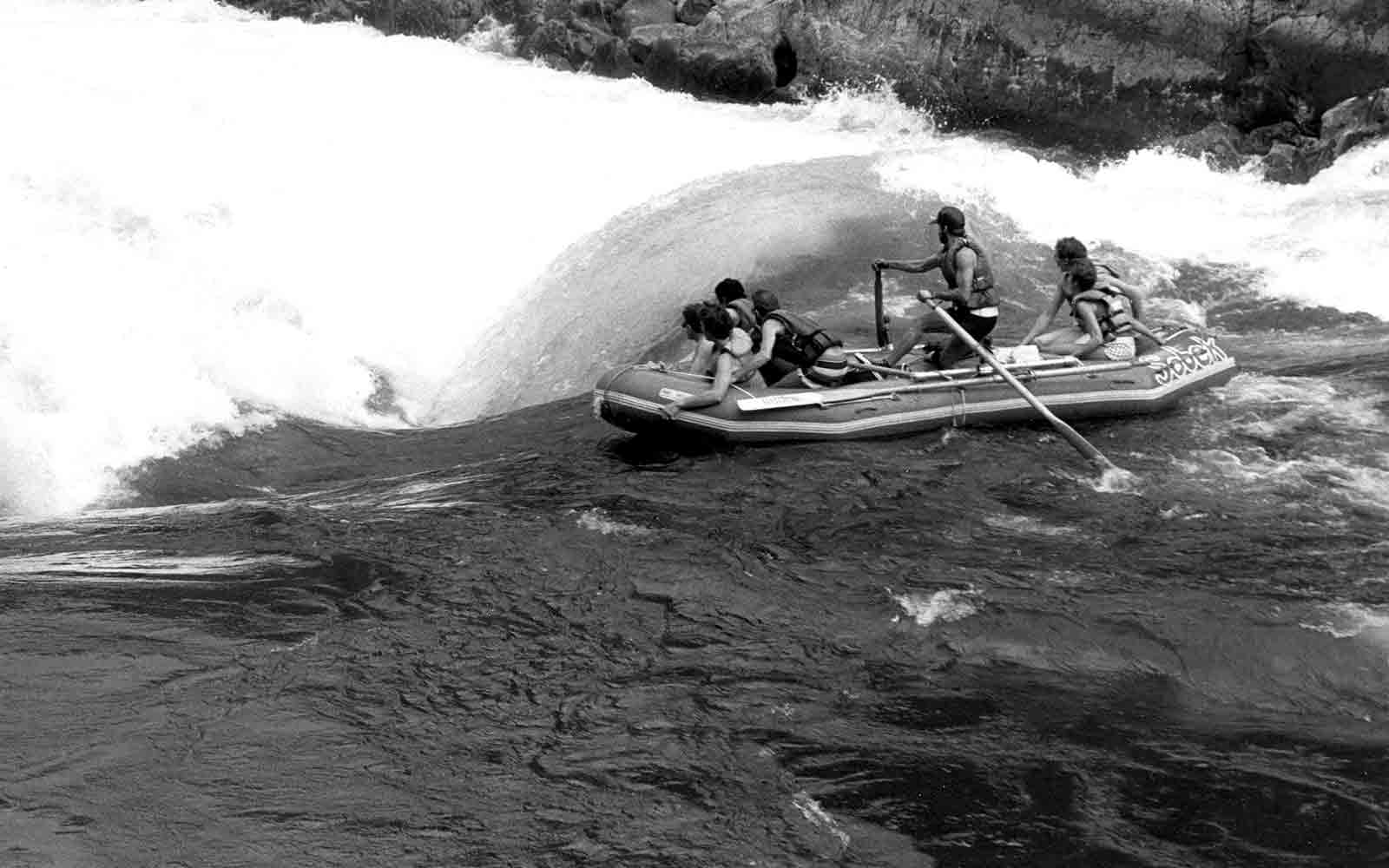 About us: A group of people in a raft on a river.
