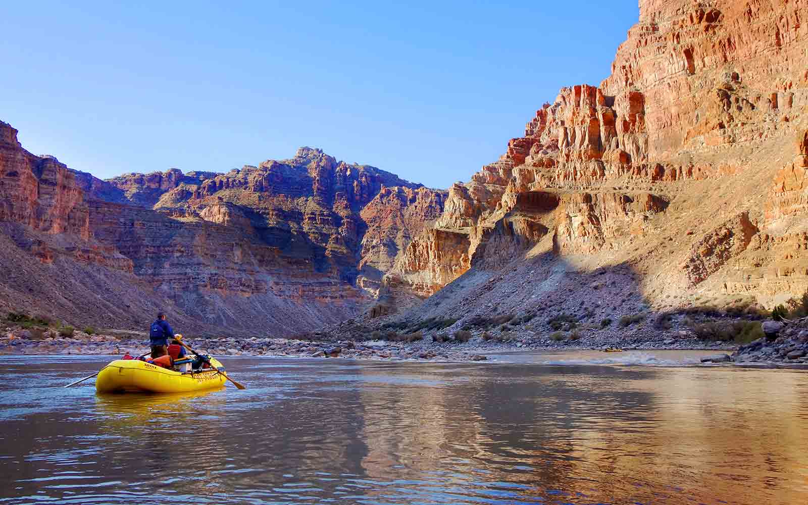 A person is paddling a yellow kayak in the grand canyon.