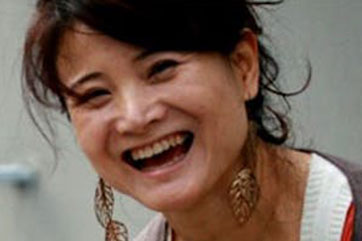 A woman is smiling while holding a camera.