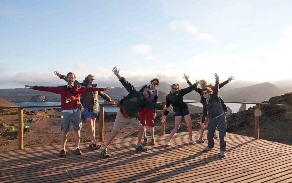 A group of people standing on a wooden deck with their arms raised.
