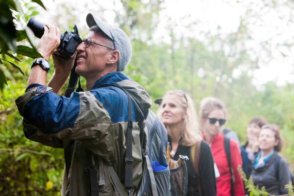 A group of people looking through binoculars in a forest.