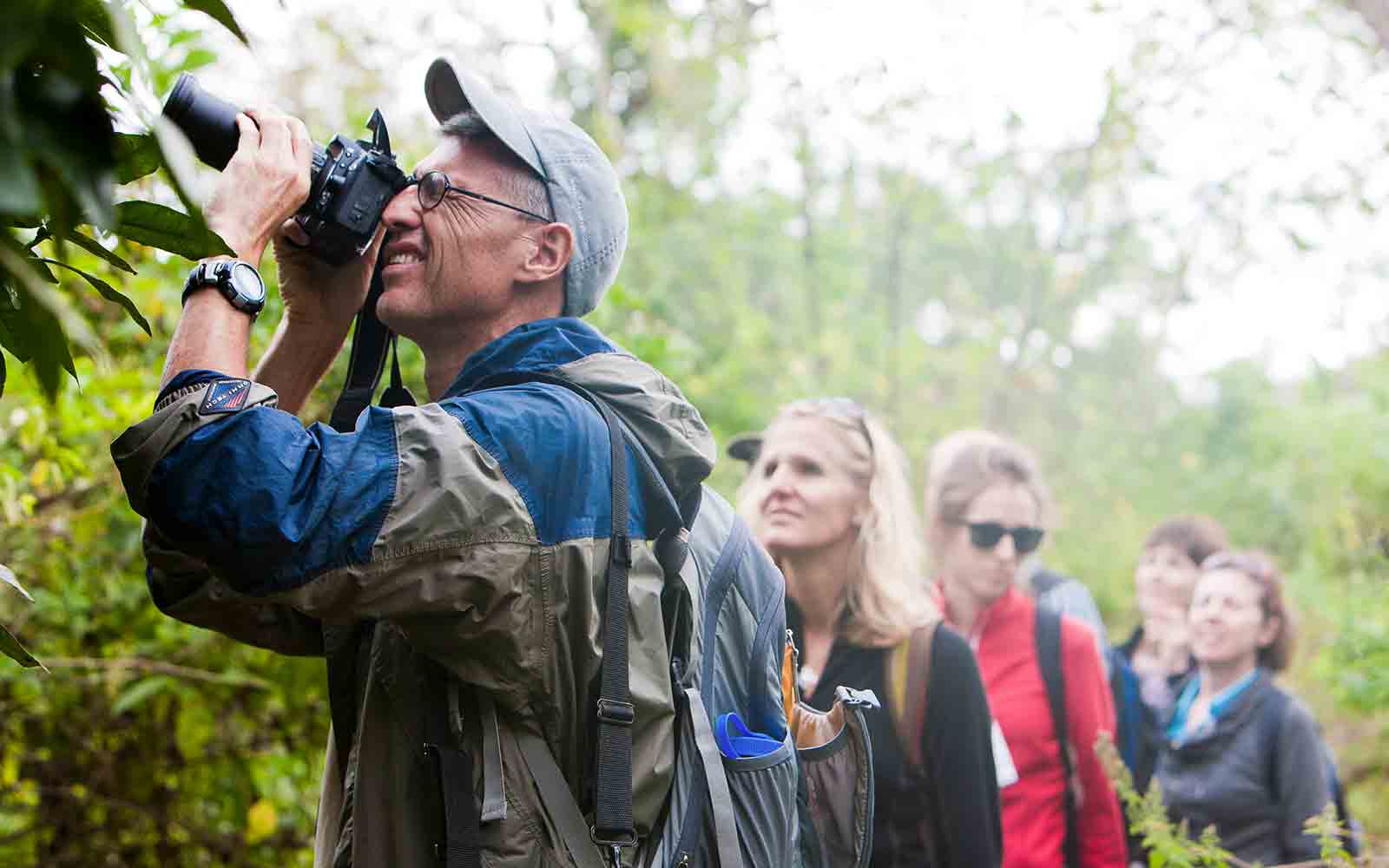 A group of people looking through binoculars in a forest.