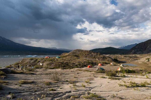 A group of tents set up near a lake and mountains.