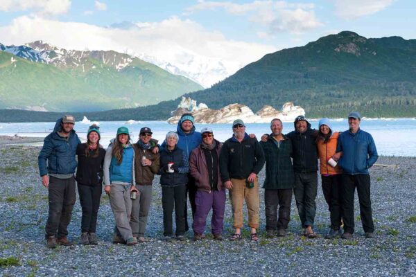 A group of people standing in front of a glacier.