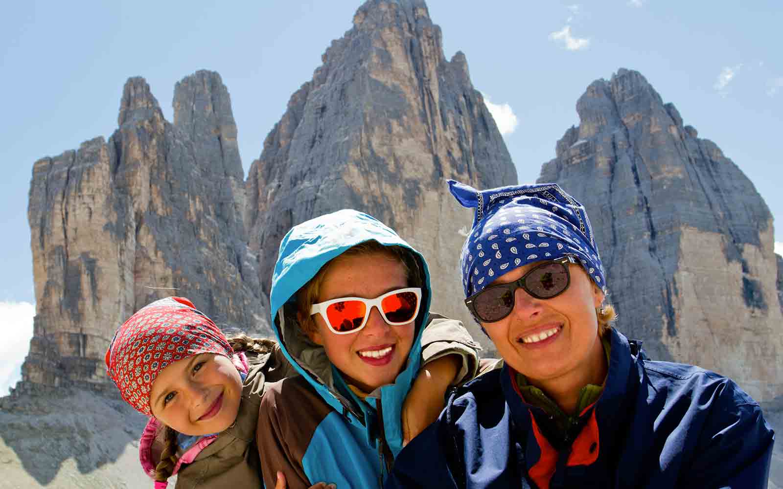 A group of people posing for a picture during hiking tours in front of a majestic mountain.