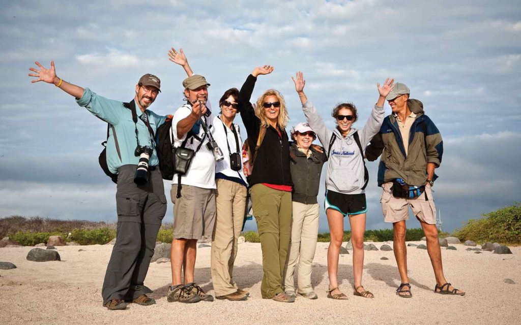 A group of people on an adventure cruise posing for a photo on the beach.