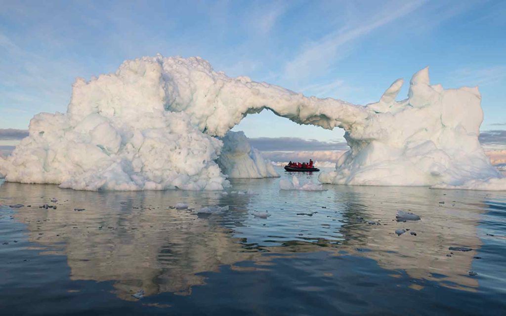 An iceberg in the water with a boat in it, offering an exciting adventure cruise experience.