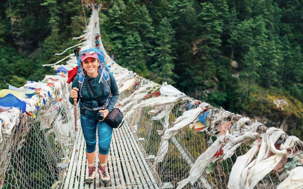 A woman walking across a suspension bridge in nepal.