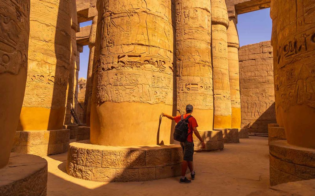 A man looking at the pillars of a temple in egypt.