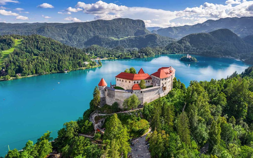 The castle on top of a mountain overlooking a lake in Bled, Slovenia offers breathtaking views for hiking enthusiasts exploring Europe's natural wonders.