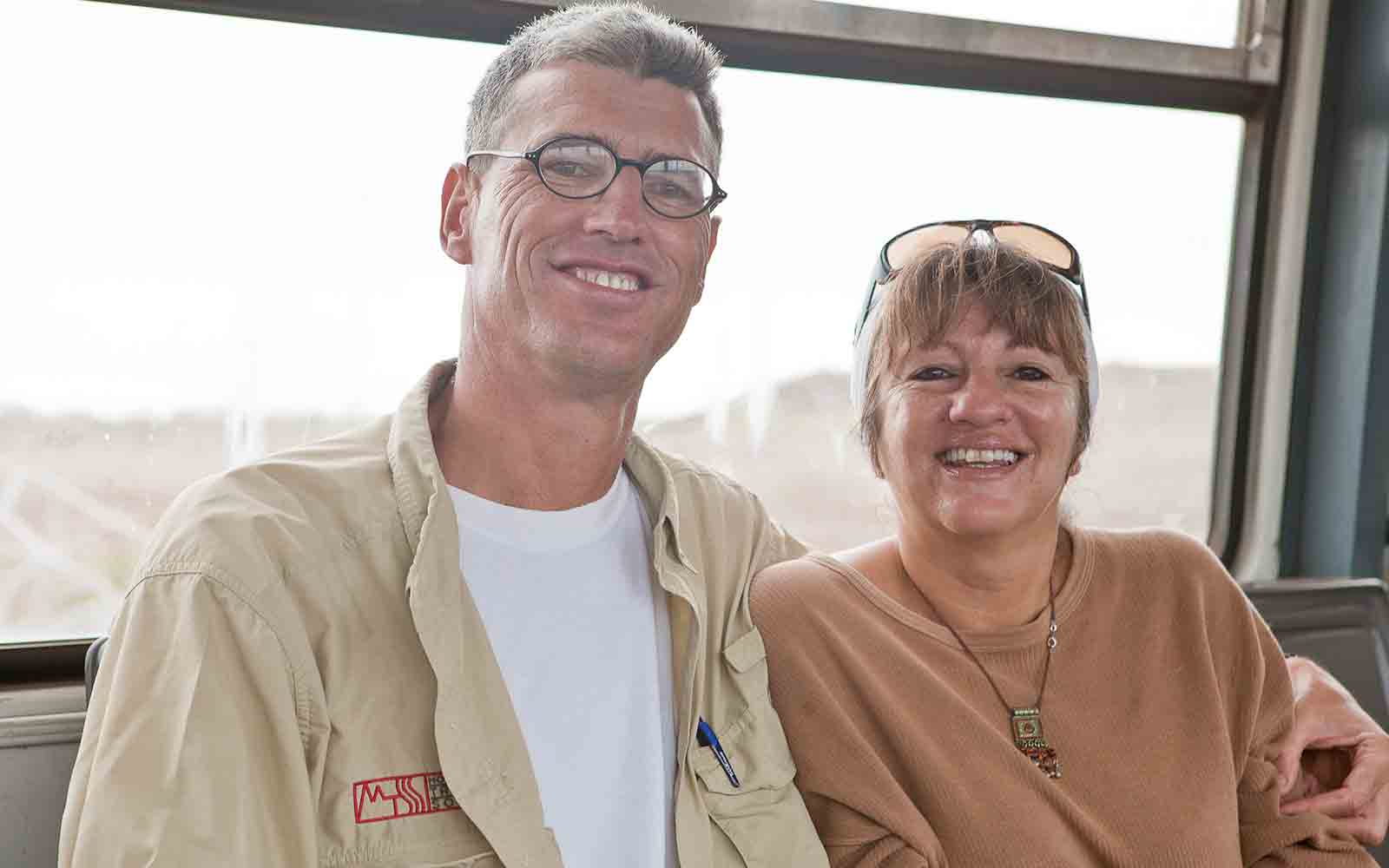 A man and woman smiling while sitting on a train.