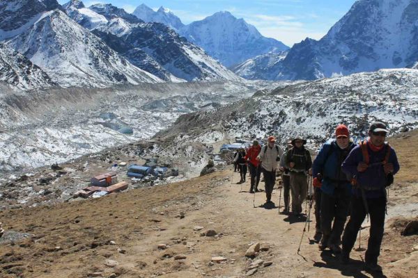 A group of people on a Nepal trekking adventure, hiking up a trail with mountains in the background.