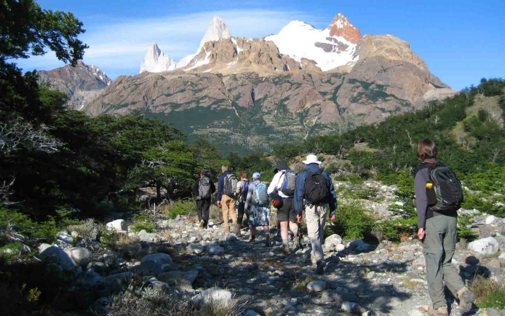 A group of people on an active adventure, hiking on a trail with mountains in the background in Patagonia.