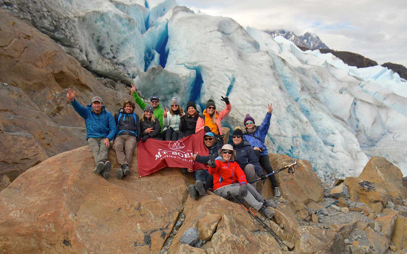A group of people posing in front of a glacier.
