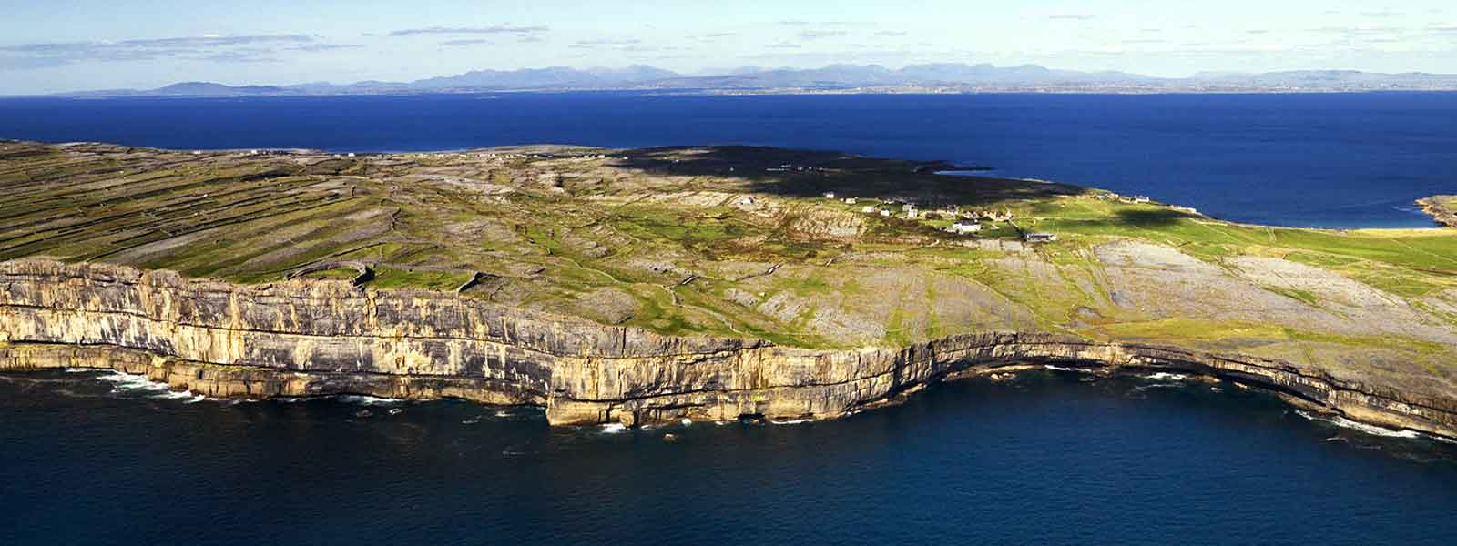 An aerial view of a cliff amidst the picturesque waters of Ireland draws visitors for thrilling adventure tours.