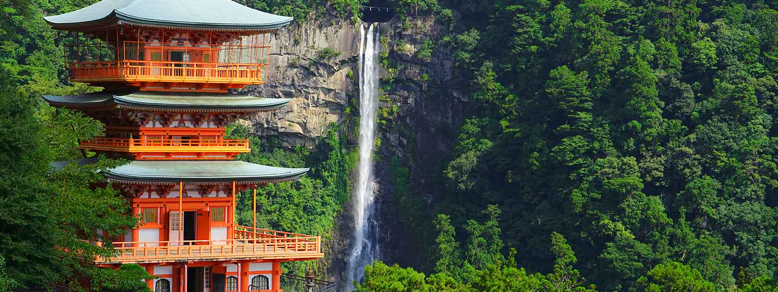 A pagoda with a waterfall in the background.