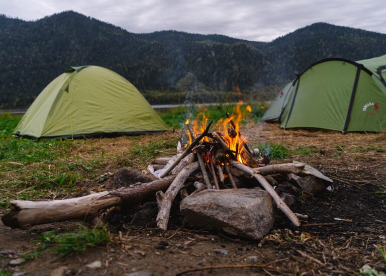 campfire with green tents across from it 