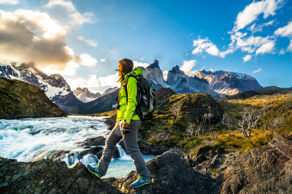 A woman is hiking in the mountains near a waterfall.