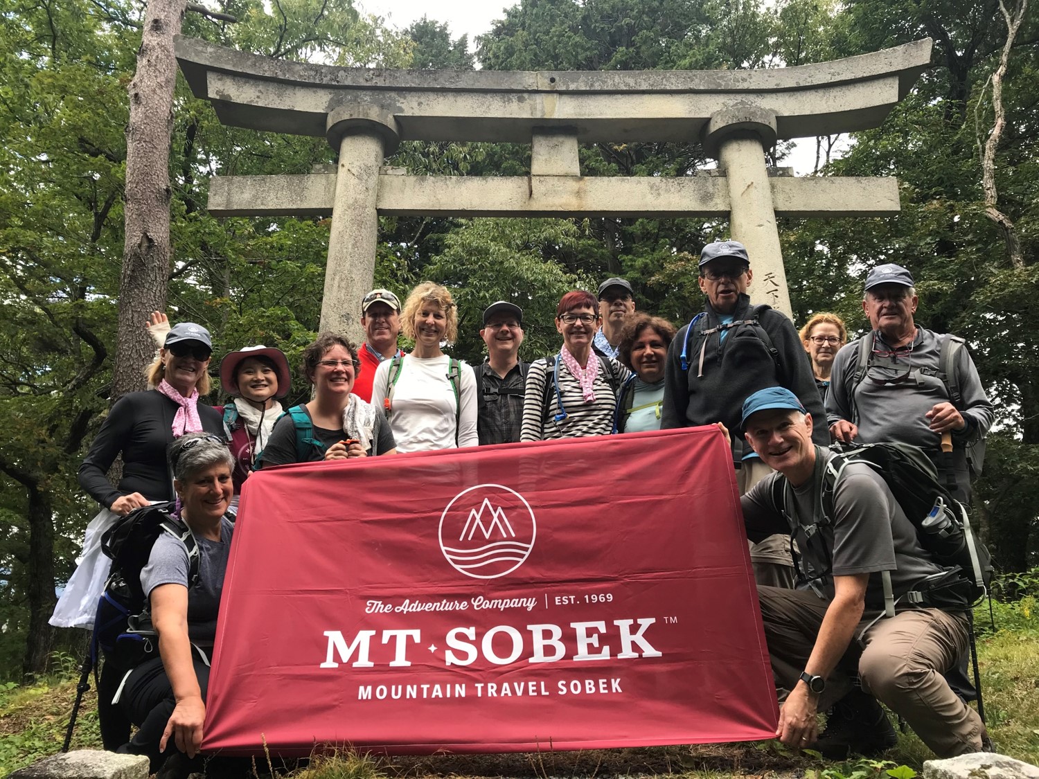 A group of people from an adventure travel company posing in front of a torii gate.
