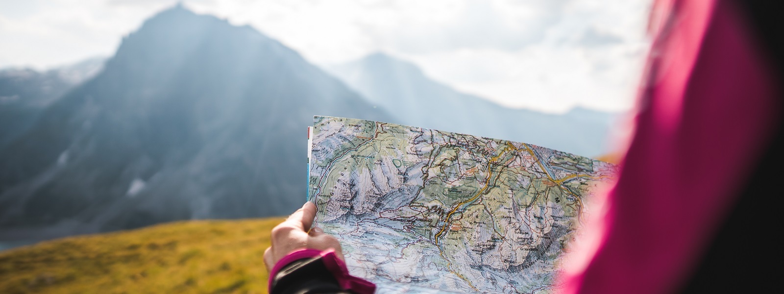 A woman holding a map in front of mountains, embarking on Saved Trips with MT Sobek.