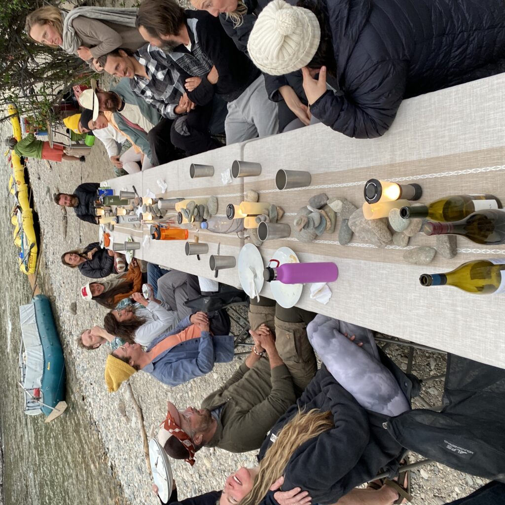 Large group of travelers seated around a wide table in the Middle Fork of the Salmon River in Idaho