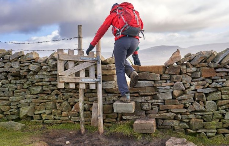 Tourist climbing ancient standing stones in an ever-changing, beautiful England scenery / MT Sobek