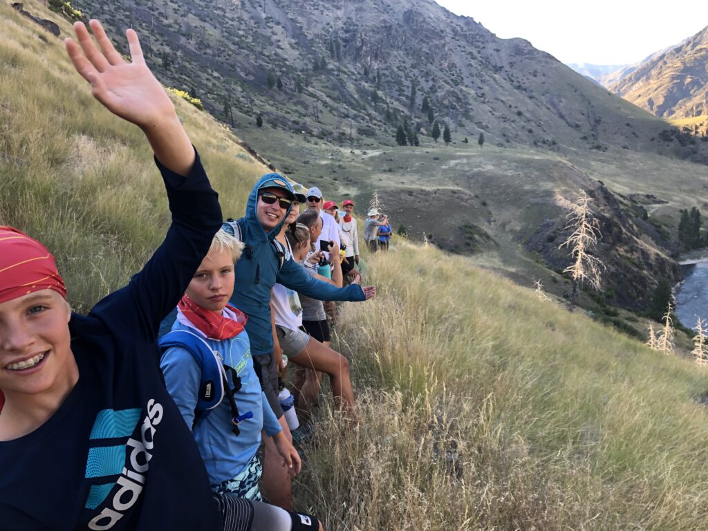 A group of hikers waving their hands on the middle fork of a mountain in Idaho.