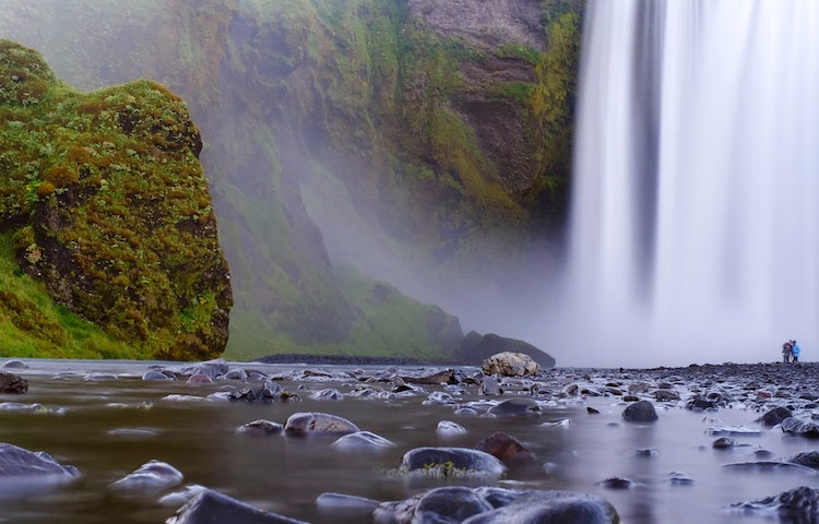 Tourist exploring a waterfall in a hut to hut hiking guided adventure in Iceland's eastern fjords