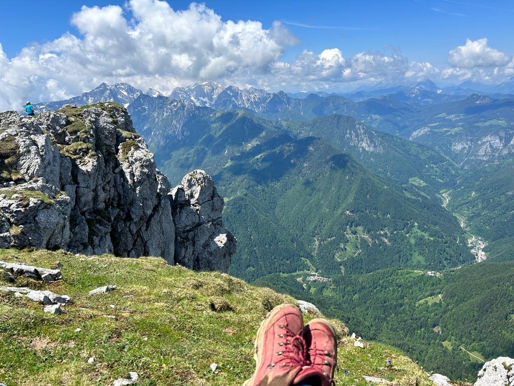 Hiker with red hiking shoes sitting near the ledge in the Raduha Mountain Range in Slovenia