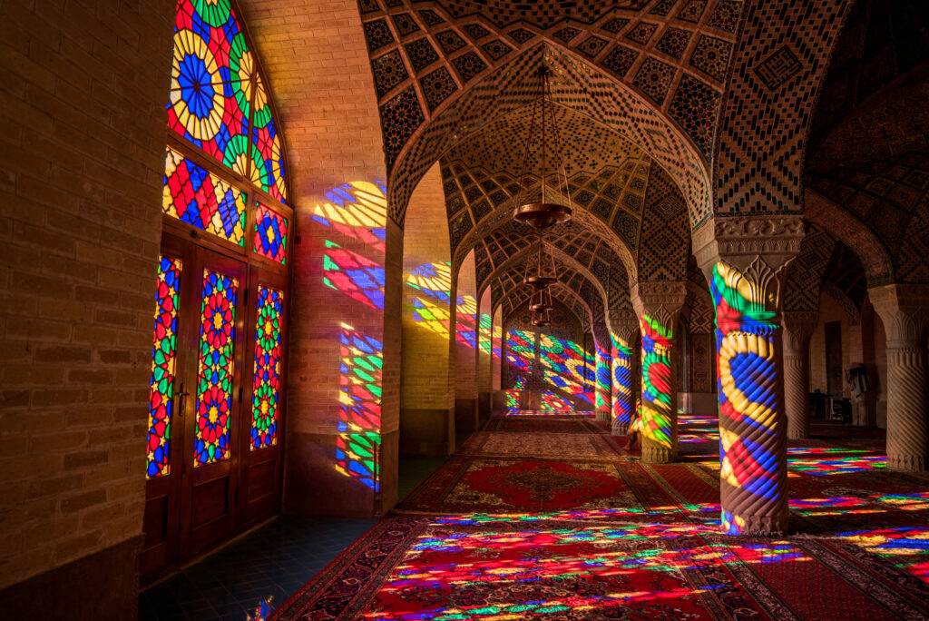 Colorful light through stained glass window inside Nasir Al-Mulk Mosque, a traditional mosque in Shiraz, Iran.