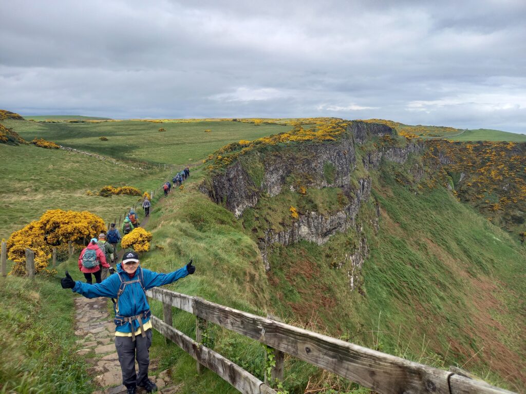 A group of people standing on a wooden boardwalk on the edge of a cliff.