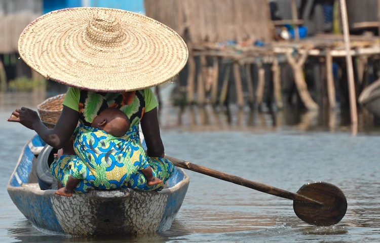 Woman in traditional West African clothes on a boat with her child in West Africa