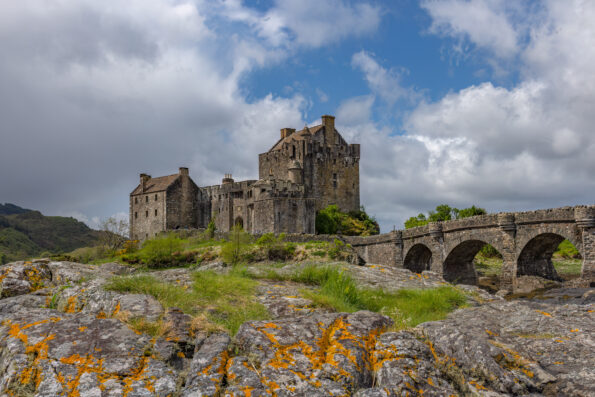 A castle sits on top of a rocky hill in scotland.
