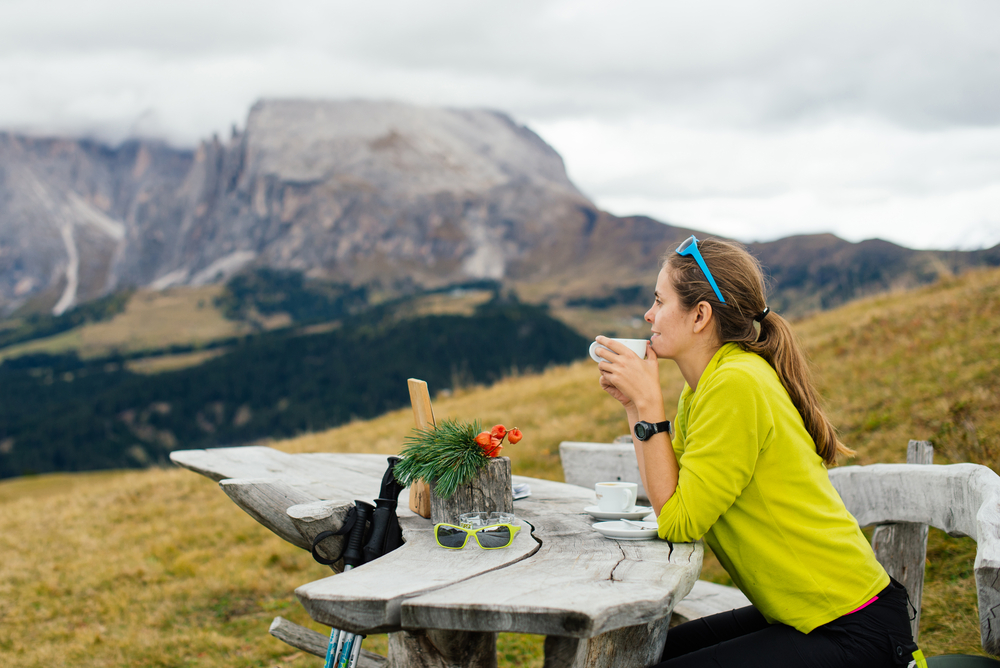 Girl tourist drinking delicious coffee and admiring the views of the Dolomites in the Alps region in Italy, Europe