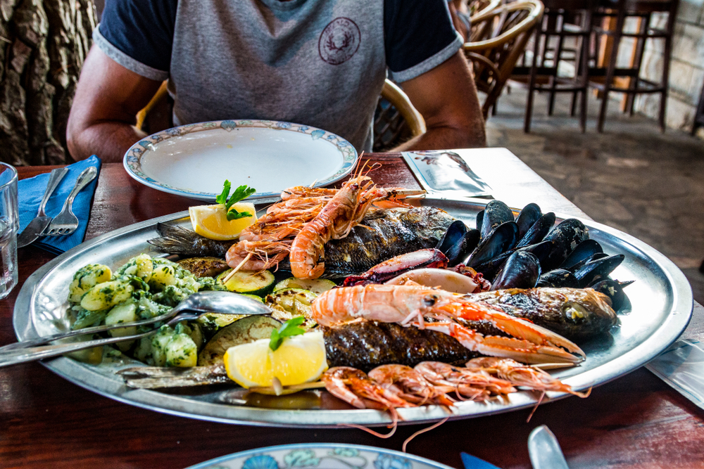 A man sitting at a table with a plate of seafood.