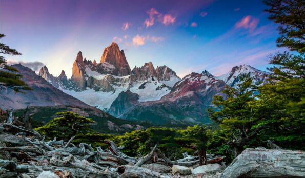 The best adventures in Patagonia await at an awe-inspiring mountain, adorned with magnificent trees, that serves as the backdrop to a captivating sunset.