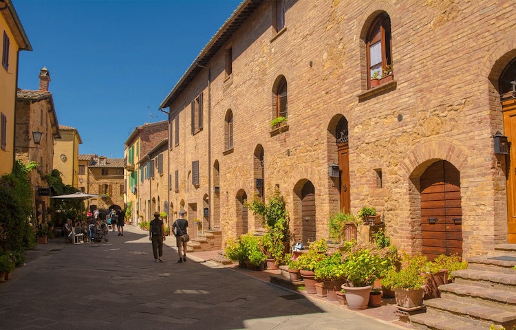 Man and companion walking in age-old village of Pienza in Italy, Europe