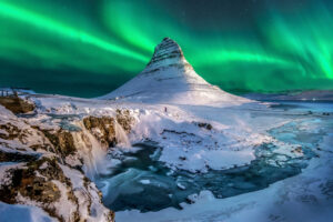 An aurora bore over a mountain in iceland.