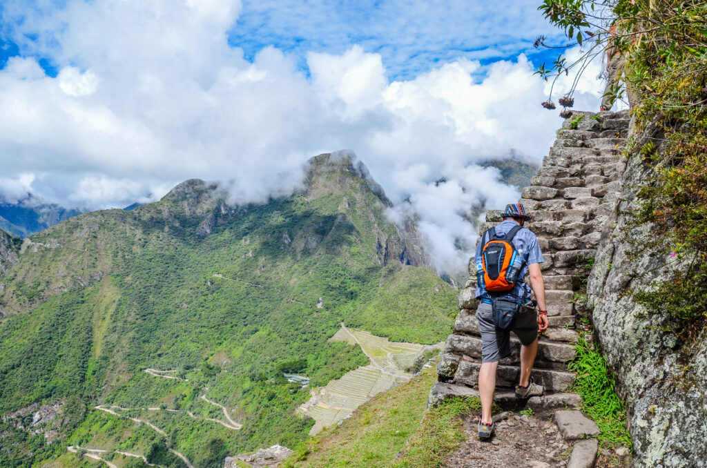 Male Tourist climbing Huayna Picchu mountain for one of the best panoramic views of Machu Picchu