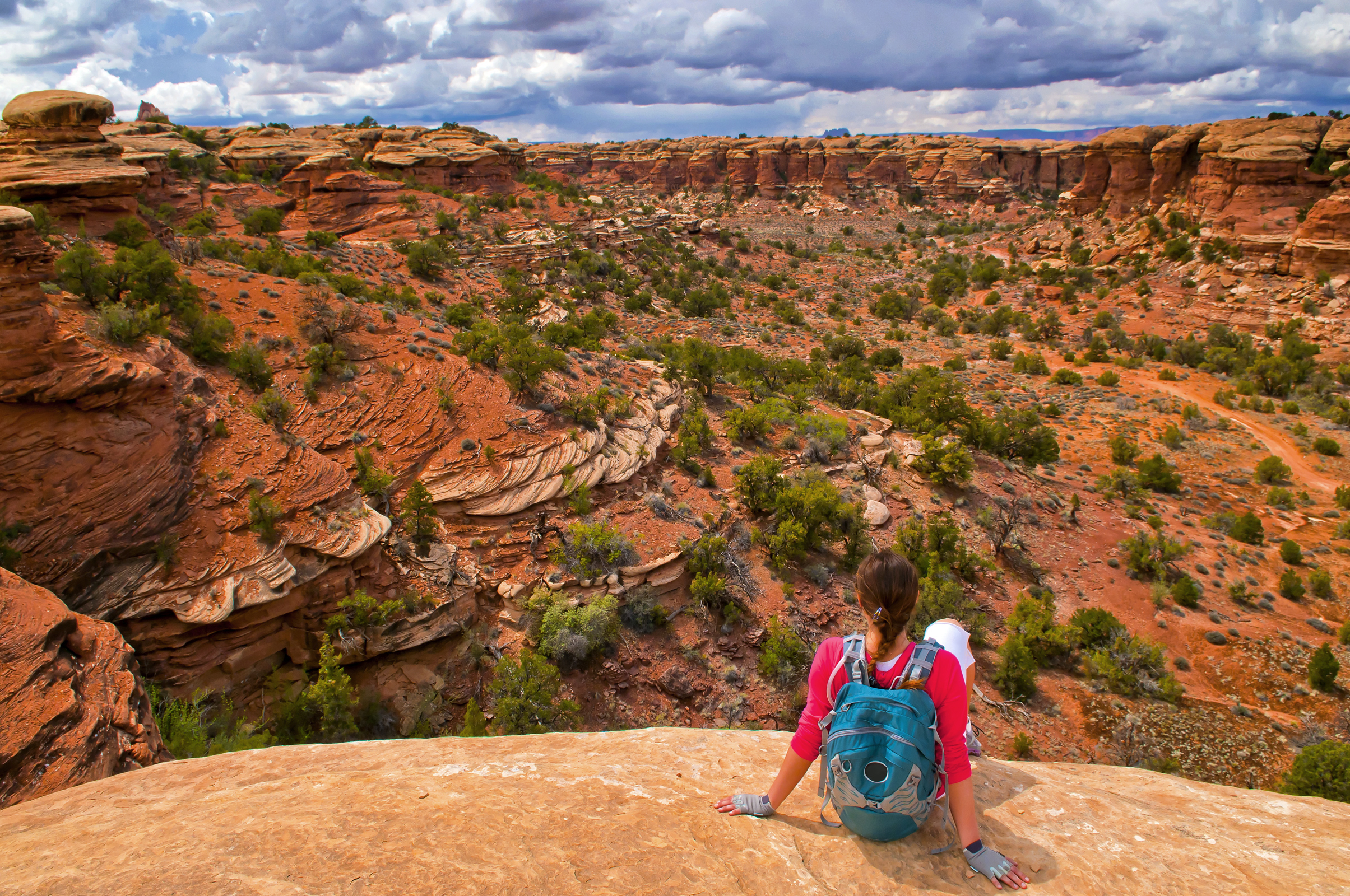 Hiking Girl sitting on the edge of the cliff on Elephant Hill Canyonlands Needles District Utah