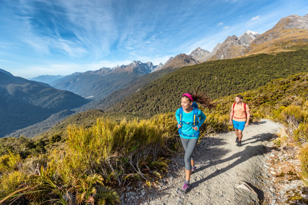 two solo travelers female and male hiking on a trail in South Island, New Zealand, in Fiordland National Park, a pristine wilderness