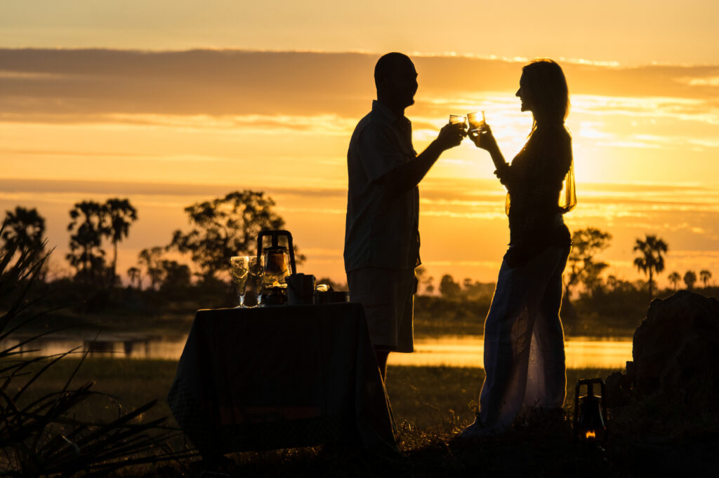 Female and male travelers enjoying sundowners at Okavango Delta, Botswana, Africa