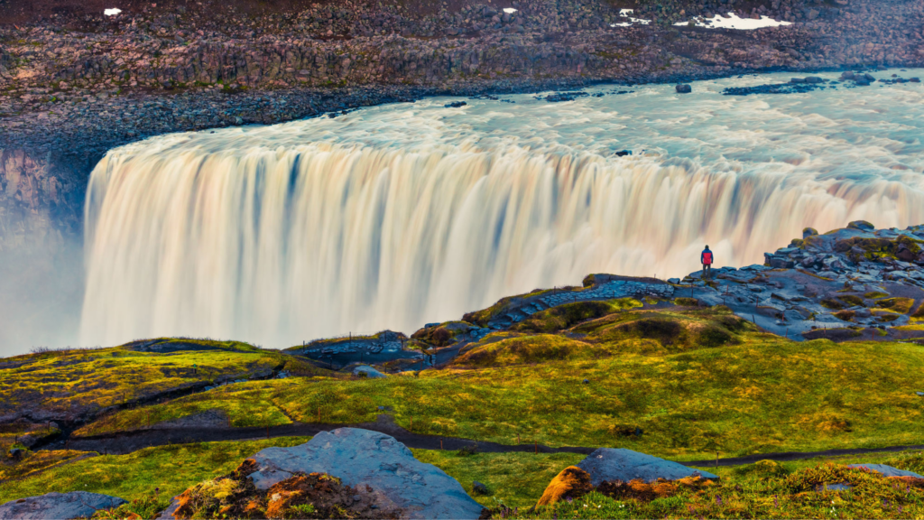 female solo traveler hiking to Ireland's legendary natural wonders like the Dettifoss Waterfall in the summertime in Iceland, Europe