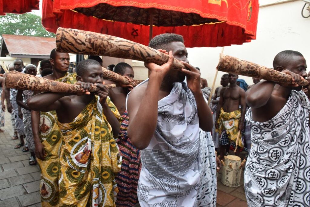 Group of men in traditional African robes dancing and singing celebratory songs in Ghana, Africa