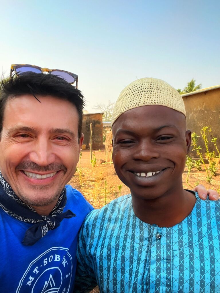 Massimo smiling widely with a nomadic camp of the Fulani, the largest tribe of Zebu cow herders in West Africa