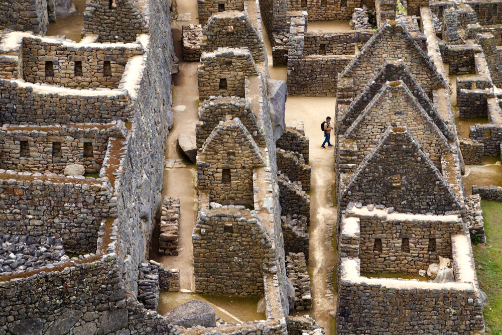 A male solo traveler wanders through the ruins of the ancient Incan city of Machu Picchu in Peru